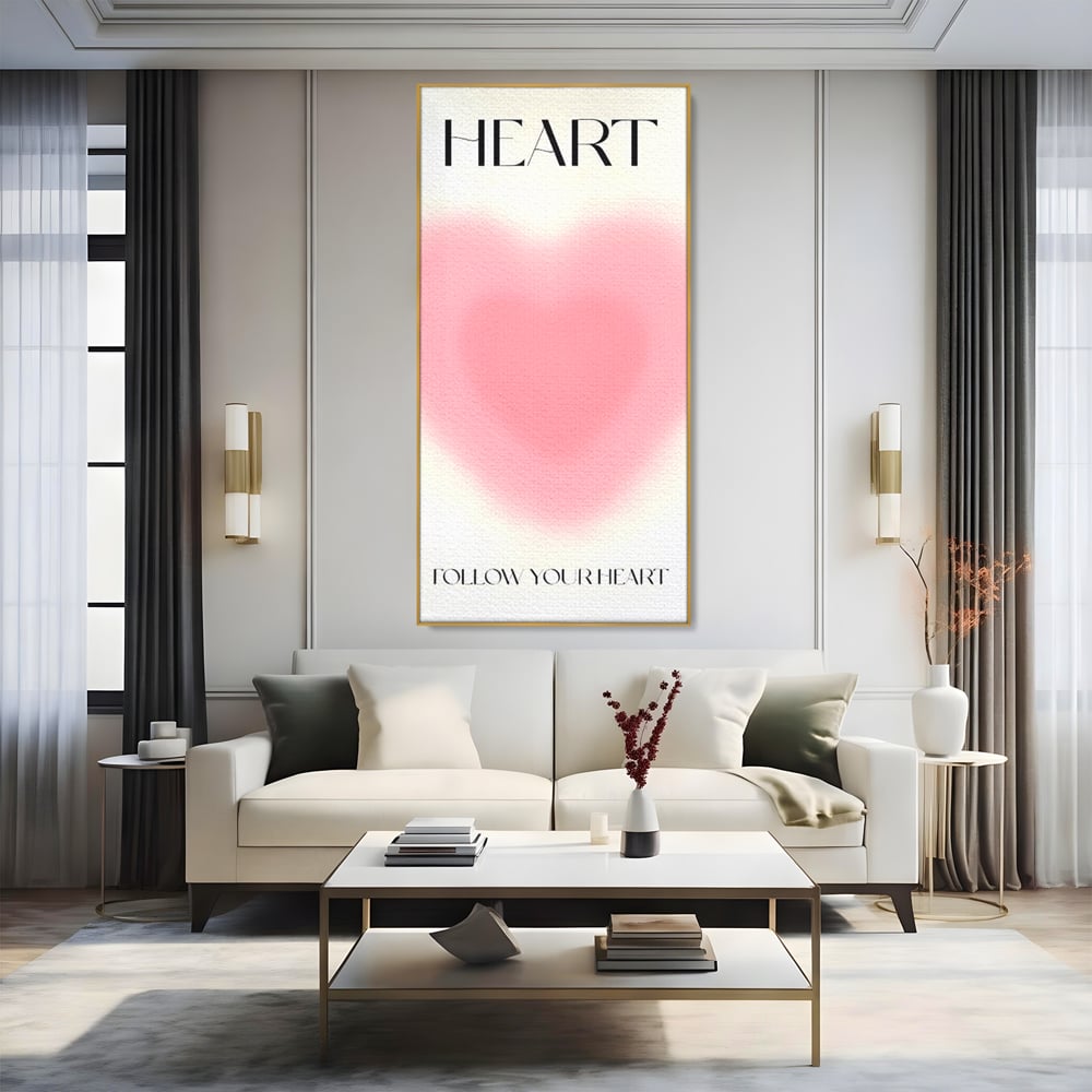 Tablou canvas cu tablou vertical cu inima roz blurata, in rama de aluminiu auriu, pe perete intr-un living